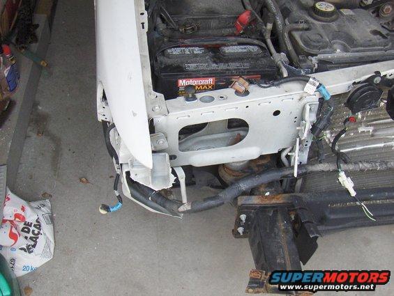 2003 Ford Crown Victoria front end with damaged bumper and fender, battery visible
