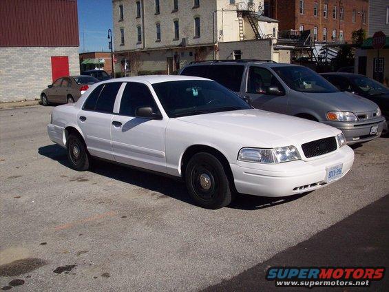 White 2003 Ford Crown Victoria parked in lot with a silver minivan behind it
