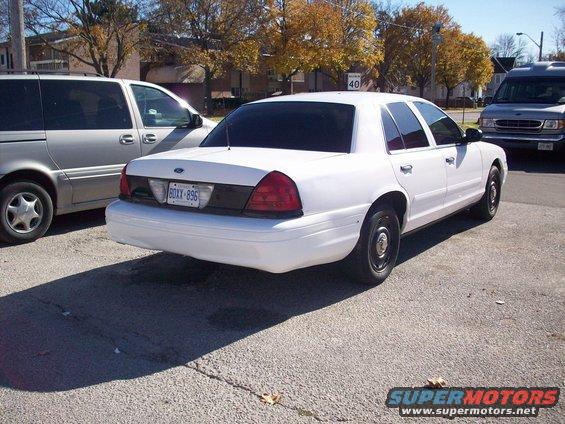 White 2003 Ford Crown Victoria sedan, rear 3/4 view, parked on asphalt