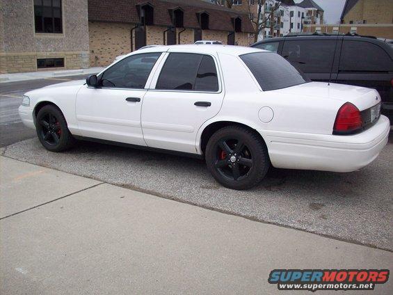 White 2003 Ford Crown Victoria sedan with black rims and red brake calipers, viewed from the side