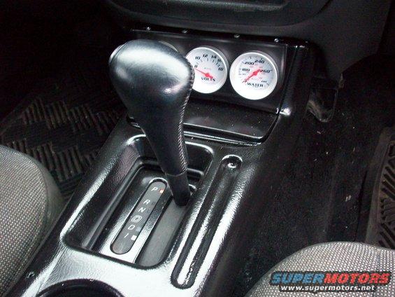 car's center console with gear shifter and two aftermarket gauges for volts and water temp