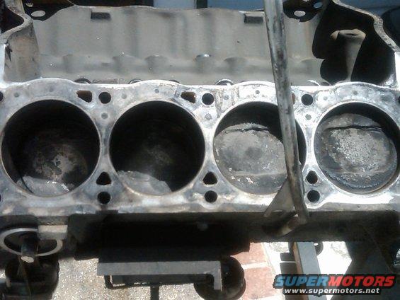 Engine block with four visible cylinders and pistons, some showing wear