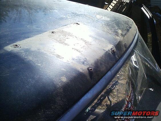 Close-up of a vehicle's hood and windshield, showing some rust spots and a chain