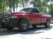 1993 Ford Bronco - This red pickup truck is parked outdoors with trees in the background.