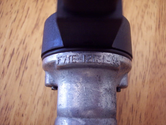 Metal part with black plastic top, showing casting numbers F7TE-12131-AA