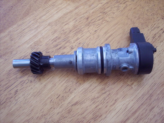 Automotive distributor with a gear on the shaft, resting on a wooden surface