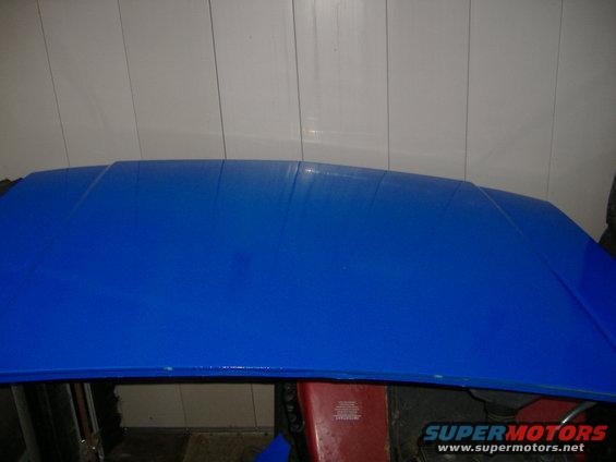 Blue car hood with some creases and a red object underneath
