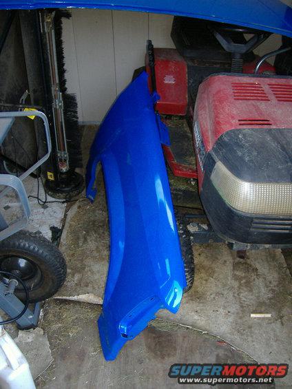 Blue fender leaning against a red lawnmower in a garage