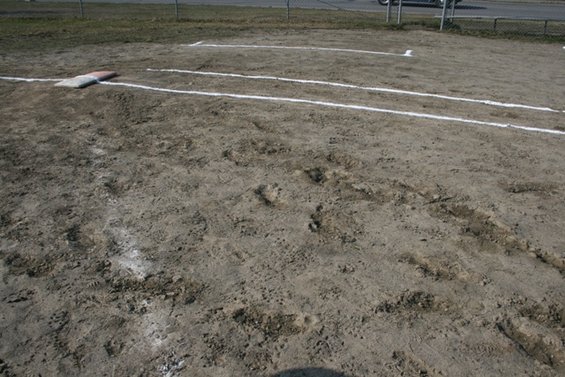 Baseball field with home plate, base lines, and tire tracks in the dirt