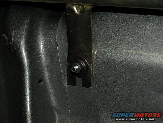 Close-up of a metal bracket secured by a bolt and nut to a textured surface