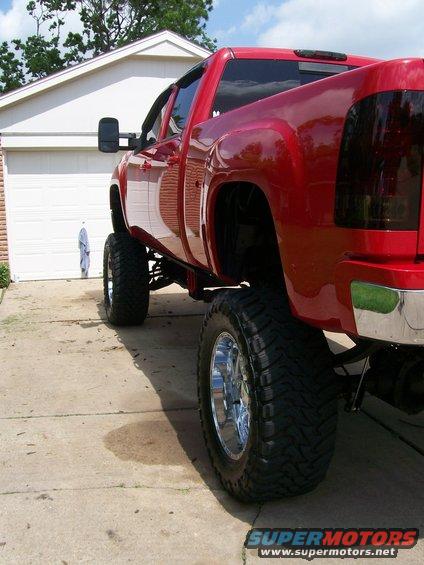 red pickup truck with large tires parked in front of a garage