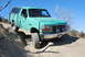 1996 Ford Bronco - A green 1996 Ford Bronco navigates a steep dirt path under a clear blue sky.