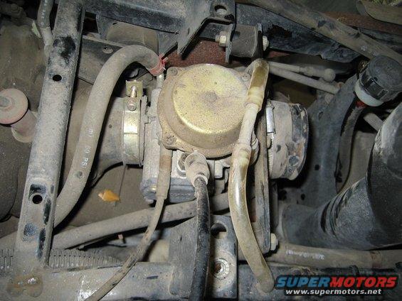 Close-up of a dirty carburetor with hoses and engine parts
