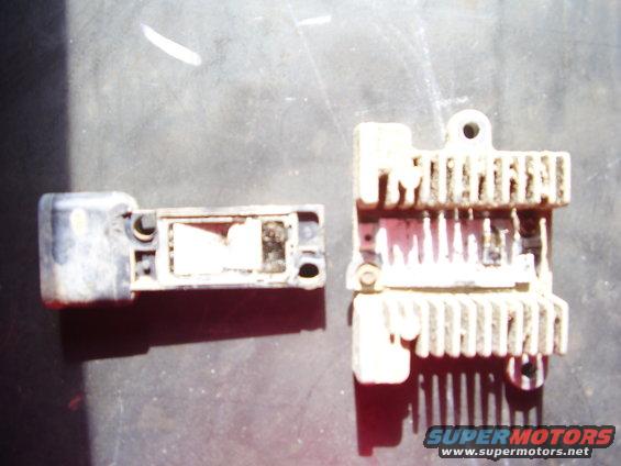 Two electronic automotive parts, one with a finned heatsink, on a dark surface