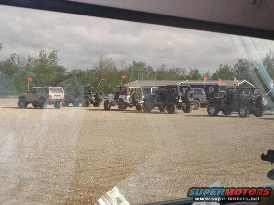 Several Jeeps and off-road vehicles parked in a lot with orange flags on poles