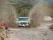 1996 Ford Bronco - A green Ford truck navigates a muddy trail, kicking up large plumes of water and dirt.