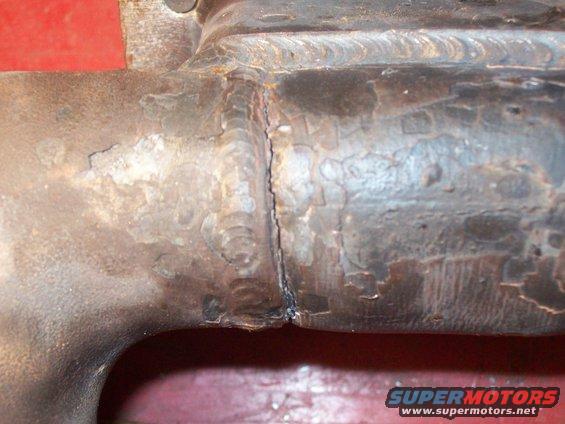 Close-up of a welded metal exhaust pipe with visible weld marks and some rust