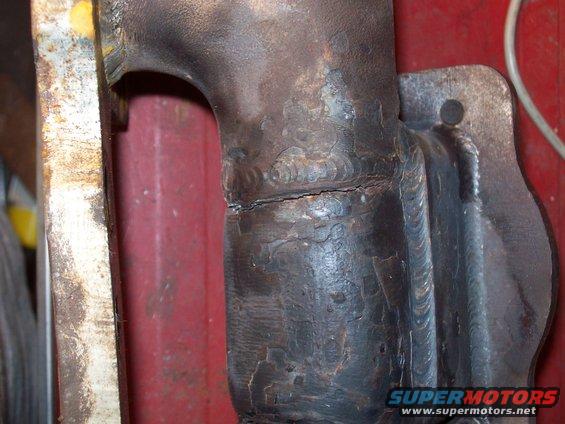 Cracked exhaust manifold with visible weld repairs