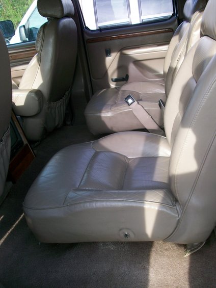 Tan leather captain's chairs and bench seats in a van interior, viewed from the side