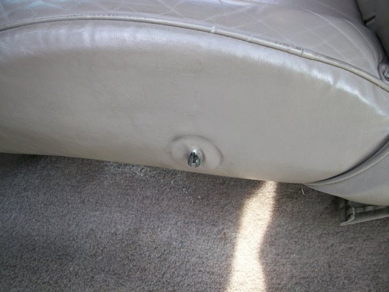 Close-up of beige leather seat trim with a metal fastener