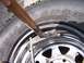 1990 Ford Bronco - A hammer is used to strike a tire valve stem on a chrome rim.