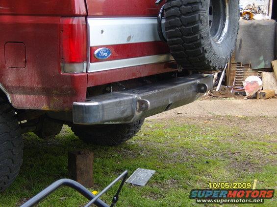Red Ford Bronco with aftermarket steel rear bumper and spare tire mounted. Visible Ford logo
