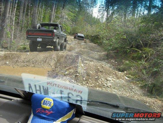 Black Ford Bronco with spare tire on back, driving on a dirt road