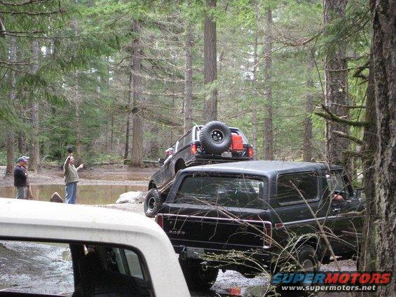 Black SUV with spare tire on roof, seen from rear