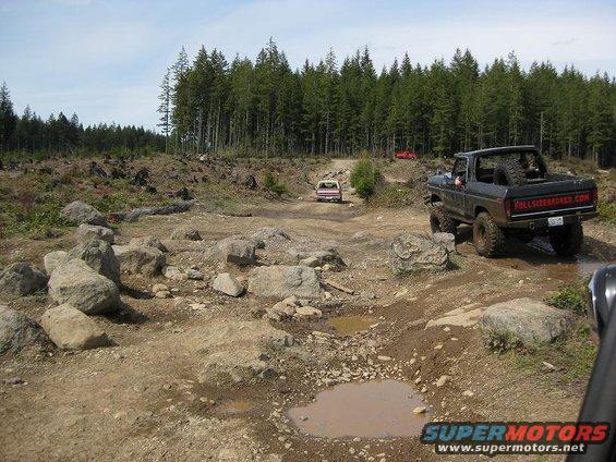 Black 1978 Ford Bronco with spare tire on back, driving off-road