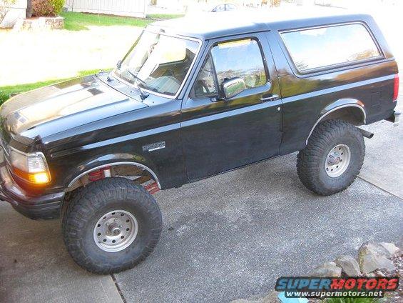 Black Ford Bronco parked on a driveway. Lifted suspension and large tires are visible