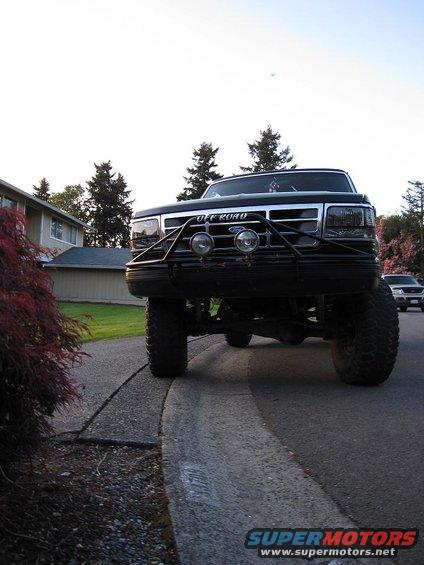 Black 1992 Ford Bronco with off-road lights and large tires, viewed from a low front angle