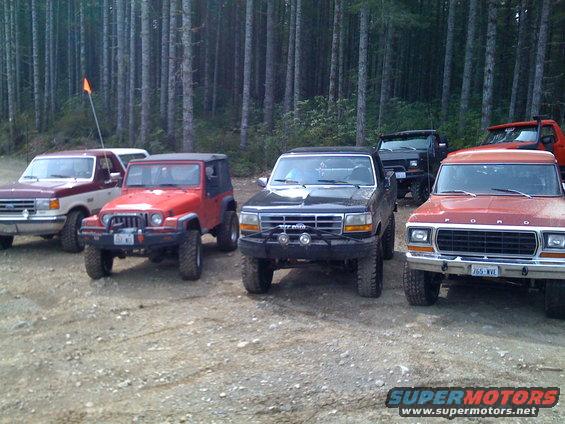 Red Ford truck with a grille from the 1970s parked in front of other vehicles