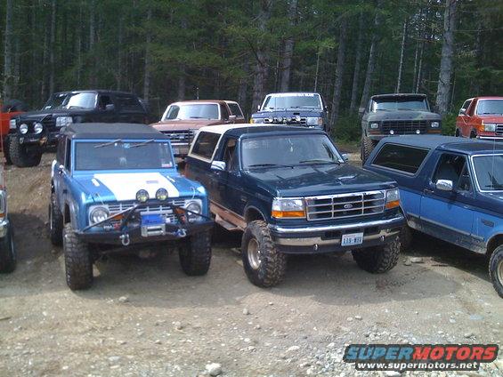 Blue 1992 Ford Bronco with off-road lights and winch, parked next to a dark green Bronco