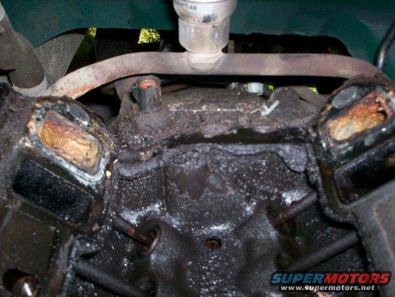 Close-up of a dirty engine block showing corroded cylinder heads and internal components