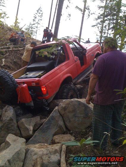 red SUV going over rocks on a trail, people watching