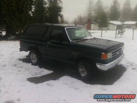 Dark green 1987 Ford Bronco parked in snow, front 3/4 view