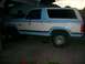1982 Ford Bronco - This two-tone blue and white SUV is viewed from the side, showing its tinted windows and a step bar below the doors.