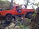 1989 Ford Bronco - A red Ford Bronco navigates a rocky trail with a person in the driver's seat.