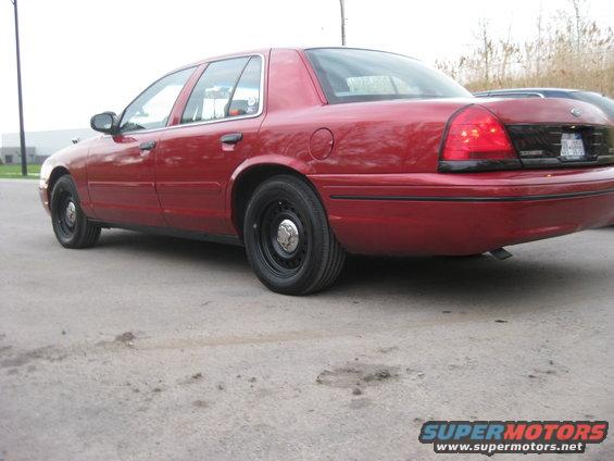 Red sedan parked on pavement. Rear quarter panel and taillight are visible