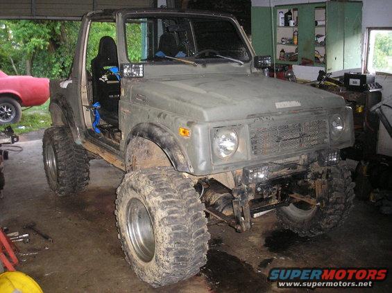 1987 Suzuki Samurai with large off-road tires and modified suspension, parked indoors
