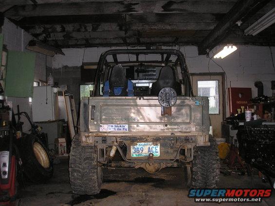 Rear view of a lifted off-road vehicle with large tires, spare tire mount on the tailgate, and a license plate reading '389 ACE'