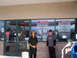 1970 Mercury Cougar - Two men stand outside a store entrance with promotional signs displayed in the windows.