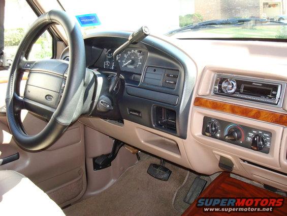 Tan interior of a 1992 Ford F-150/Bronco, showing steering wheel, dashboard, radio, and climate controls