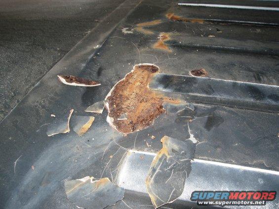 Dark gray vehicle roof panel with extensive rust and peeling paint, showing horizontal ridges
