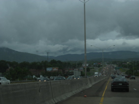 Highway traffic under a cloudy sky with mountains in the background