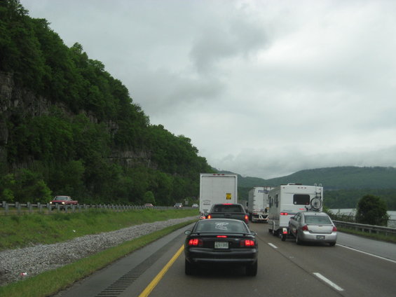 Traffic jam on a highway with a black car in the foreground, RV, and trucks