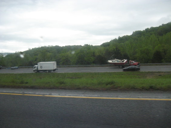 Truck towing a boat on a highway with a box truck and car also on the road