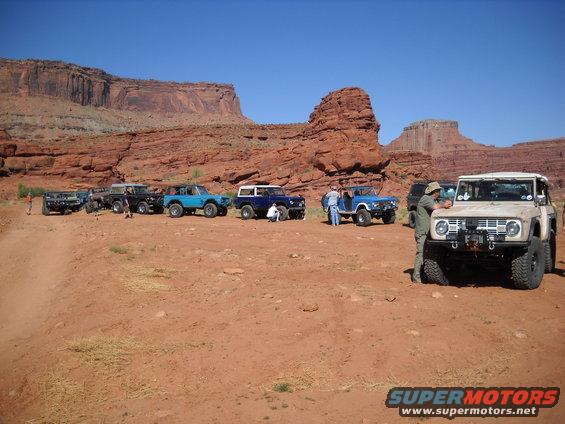 Tan Ford Bronco with winch, parked on dirt road with red rock formations behind