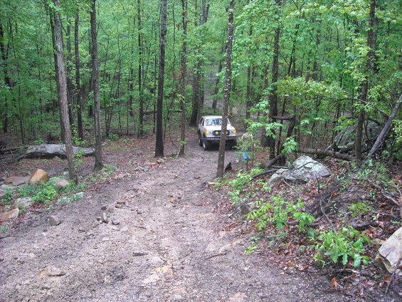 Tan SUV on a muddy forest trail