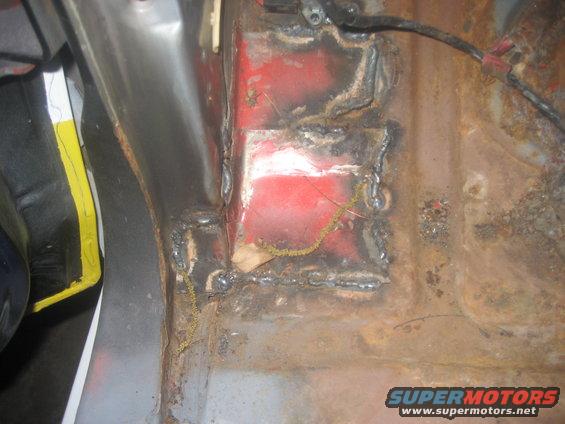 Welded metal floor pan with rust and red paint